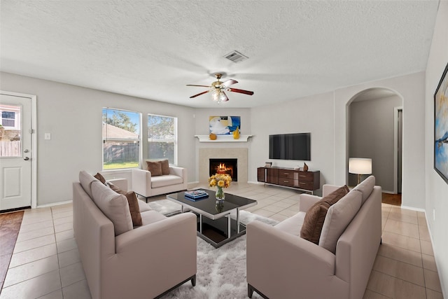 living room featuring light tile patterned floors, a textured ceiling, and ceiling fan