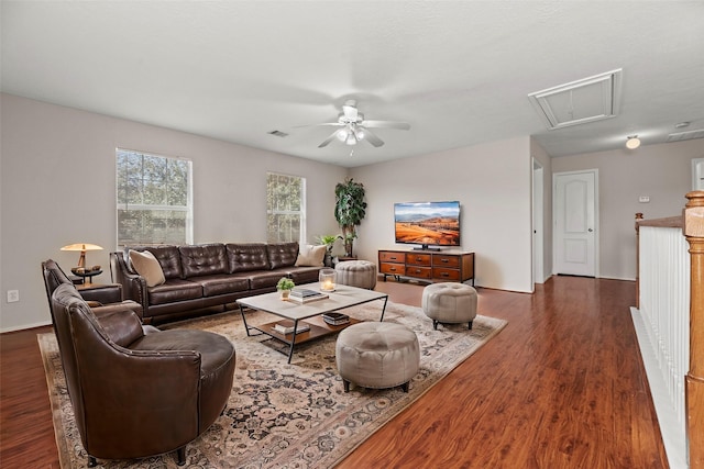 living room with dark wood-style floors, visible vents, attic access, a ceiling fan, and baseboards