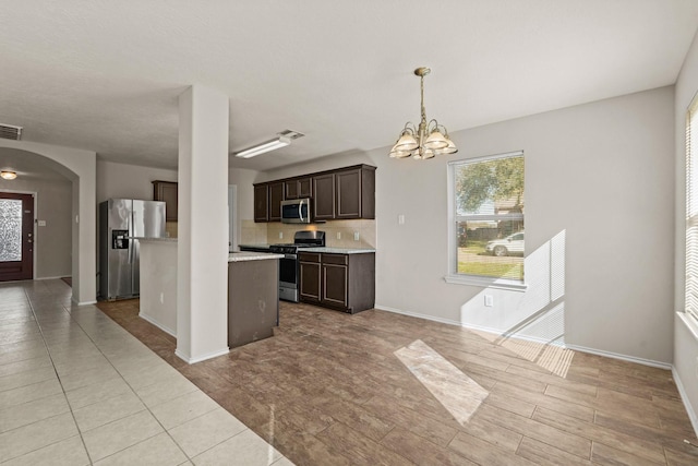 kitchen featuring a chandelier, arched walkways, visible vents, dark brown cabinets, and appliances with stainless steel finishes