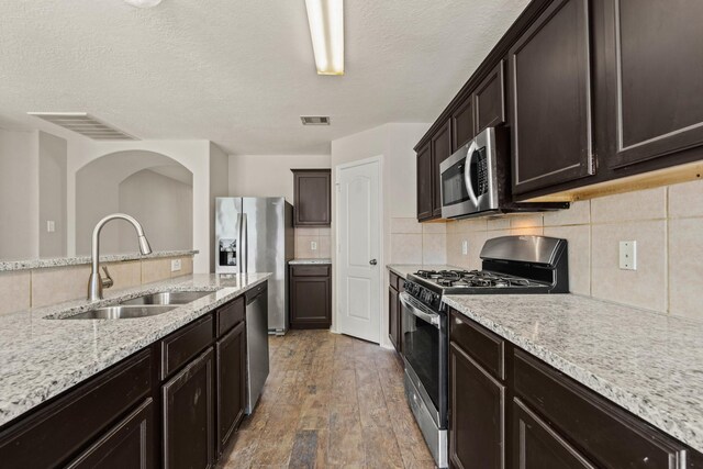 kitchen with stainless steel appliances, a sink, visible vents, light wood-type flooring, and backsplash