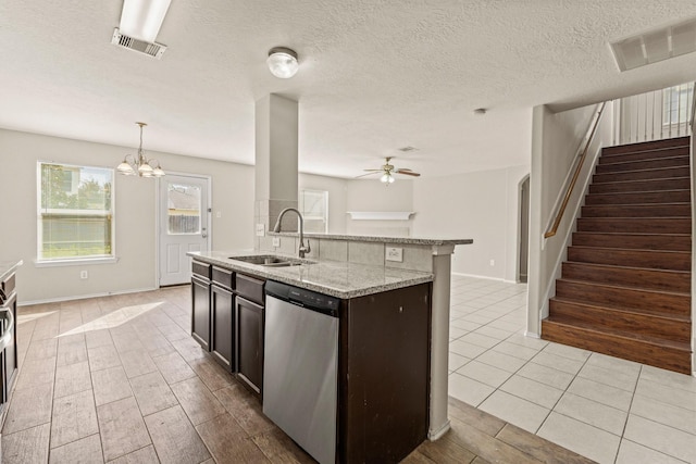 kitchen with light stone countertops, stainless steel dishwasher, visible vents, and a sink