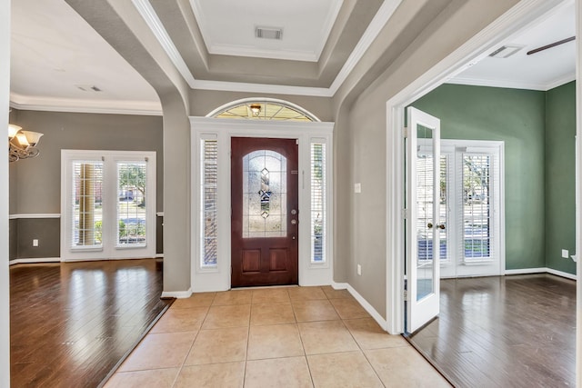 entrance foyer featuring an inviting chandelier, light hardwood / wood-style flooring, ornamental molding, and a raised ceiling