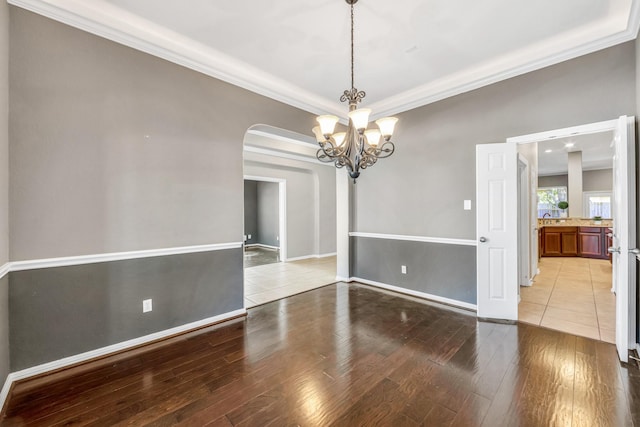 unfurnished dining area featuring ornamental molding, a notable chandelier, and light wood-type flooring