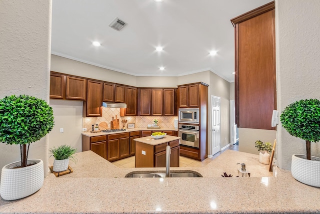 kitchen with sink, backsplash, stainless steel appliances, light stone countertops, and kitchen peninsula