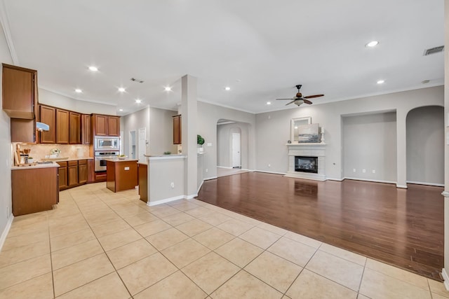 kitchen featuring light tile patterned floors, ceiling fan, stainless steel appliances, a center island, and tasteful backsplash