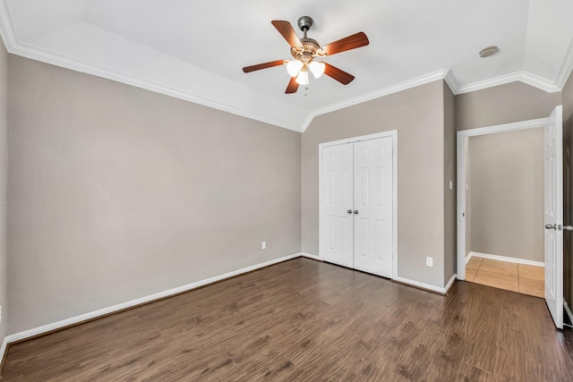 unfurnished bedroom featuring crown molding, vaulted ceiling, dark hardwood / wood-style floors, a closet, and ceiling fan