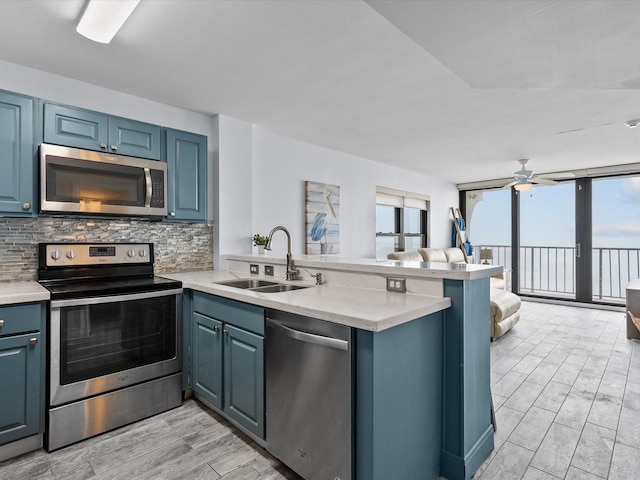 kitchen with tasteful backsplash, stainless steel appliances, kitchen peninsula, and sink