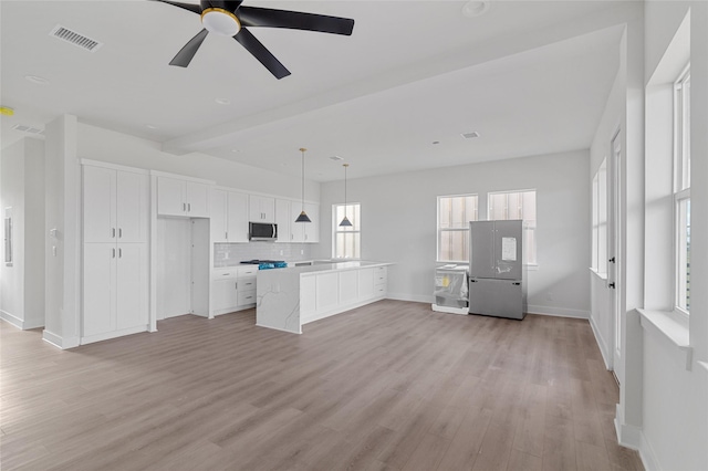 kitchen featuring a center island, tasteful backsplash, white cabinets, decorative light fixtures, and light wood-type flooring