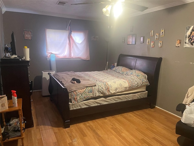 bedroom featuring wood-type flooring, ornamental molding, and ceiling fan