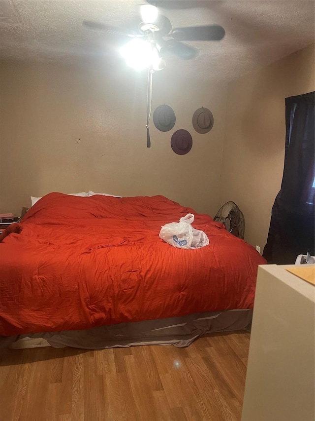 bedroom featuring hardwood / wood-style flooring, ceiling fan, and a textured ceiling