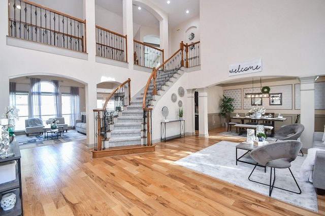 foyer featuring light hardwood / wood-style floors, a high ceiling, and ornate columns