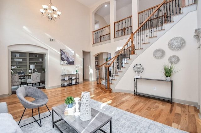 living room with hardwood / wood-style flooring, a towering ceiling, and a notable chandelier