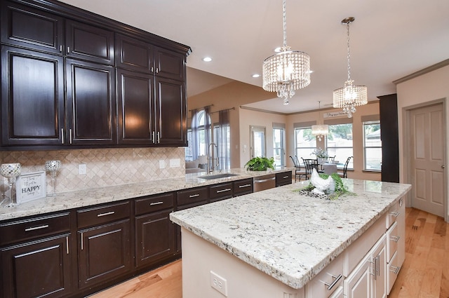 kitchen with sink, an inviting chandelier, a kitchen island, decorative light fixtures, and stainless steel dishwasher