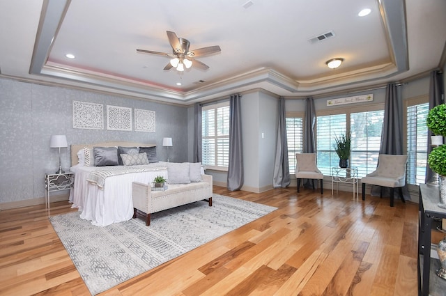 bedroom featuring a raised ceiling, crown molding, hardwood / wood-style floors, and ceiling fan