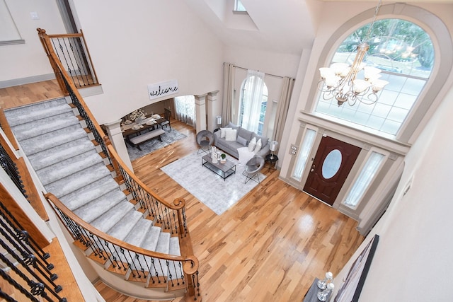 foyer featuring hardwood / wood-style flooring, a towering ceiling, and a notable chandelier