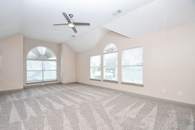 carpeted empty room featuring ceiling fan, lofted ceiling, and a wealth of natural light