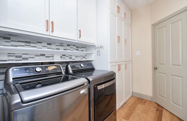 laundry area featuring cabinets, washer and clothes dryer, and light hardwood / wood-style floors