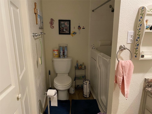 bathroom with hardwood / wood-style flooring, vanity, washing machine and clothes dryer, toilet, and a bath