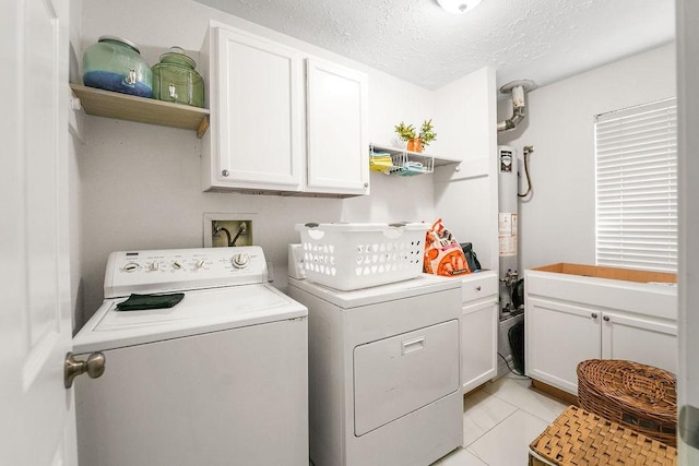 clothes washing area featuring light tile patterned floors, washer and clothes dryer, cabinets, gas water heater, and a textured ceiling