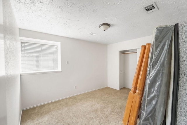 unfurnished bedroom with light colored carpet and a textured ceiling