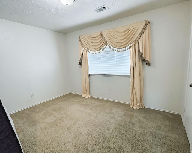 carpeted empty room with a textured ceiling