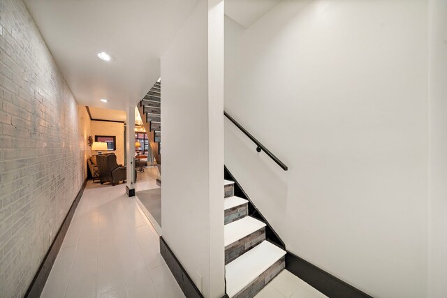 staircase featuring brick wall