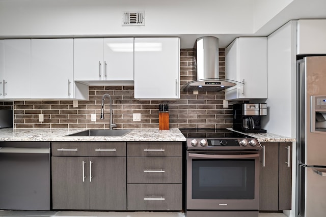 kitchen featuring appliances with stainless steel finishes, white cabinetry, sink, dark brown cabinetry, and wall chimney exhaust hood