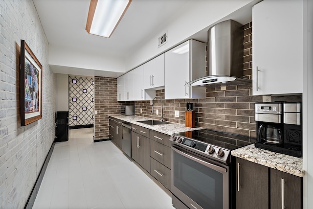 kitchen with white cabinetry, dark brown cabinetry, stainless steel appliances, and wall chimney range hood