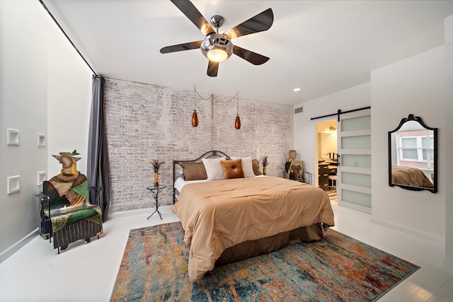 bedroom with ceiling fan, brick wall, and a barn door