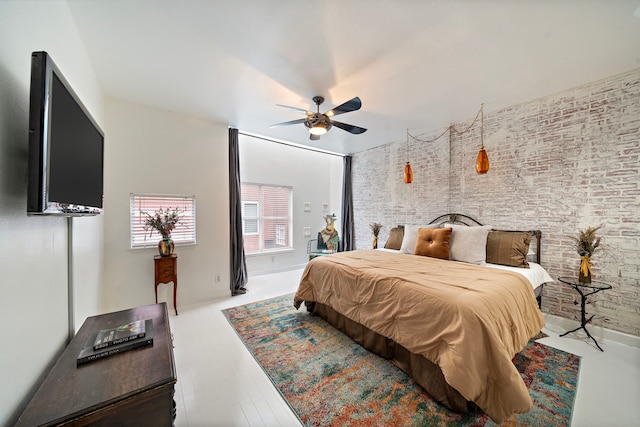 bedroom featuring ceiling fan, brick wall, and wood-type flooring