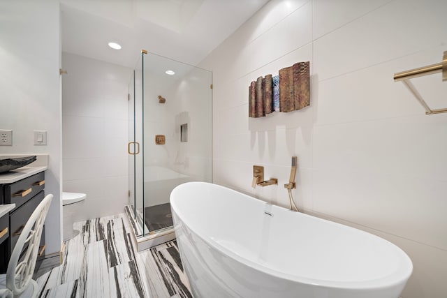 full bathroom featuring toilet, vanity, shower with separate bathtub, and tile walls