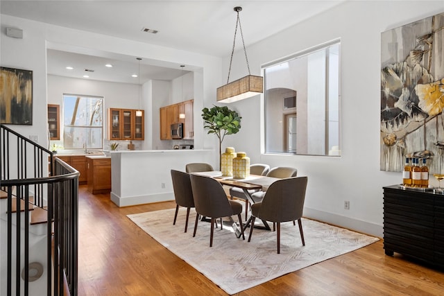 dining area featuring light wood-style flooring, stairway, baseboards, and recessed lighting