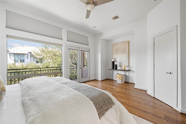 bedroom featuring access to exterior, wood finished floors, visible vents, and multiple windows