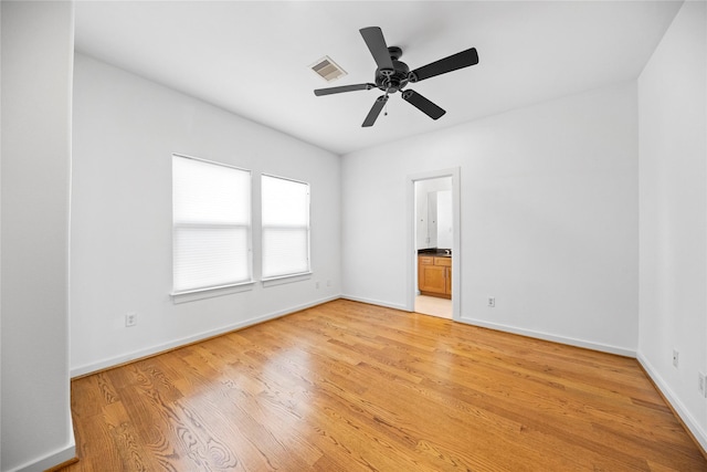 empty room featuring light wood-type flooring, baseboards, visible vents, and ceiling fan