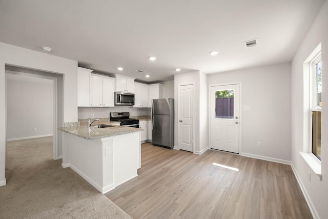 kitchen with sink, white cabinetry, stainless steel appliances, a wealth of natural light, and kitchen peninsula