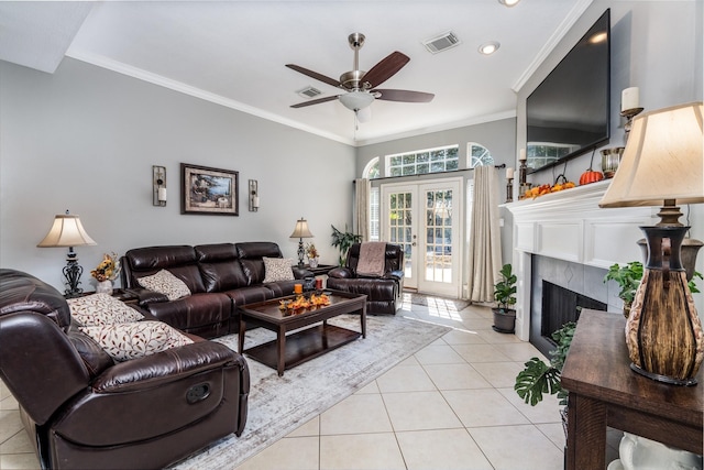 tiled living room with a fireplace, ornamental molding, french doors, and ceiling fan