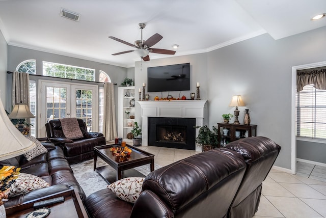 tiled living room featuring crown molding, a tile fireplace, french doors, and ceiling fan