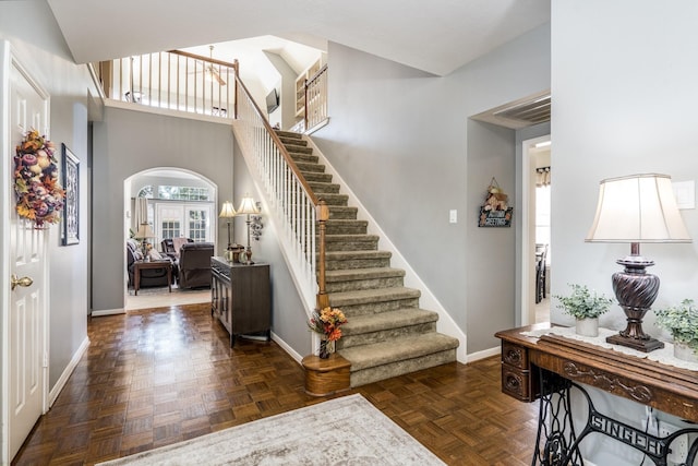 entryway featuring a towering ceiling and dark parquet floors