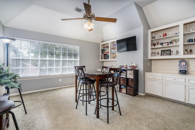 dining space featuring light carpet, vaulted ceiling, and ceiling fan