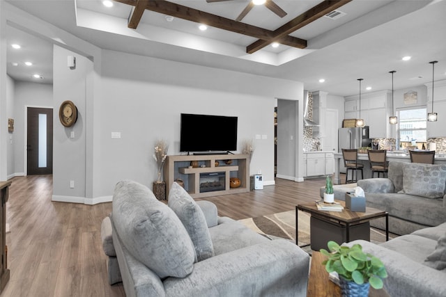 living room with coffered ceiling, beam ceiling, wood-type flooring, and ceiling fan