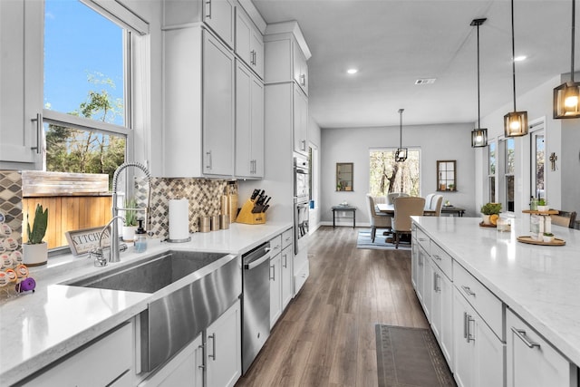 kitchen featuring pendant lighting, sink, white cabinets, stainless steel appliances, and light stone countertops