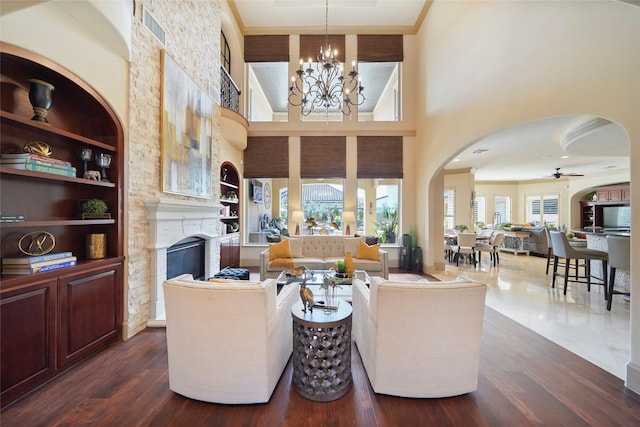 living area featuring arched walkways, a fireplace, dark wood-style floors, and visible vents