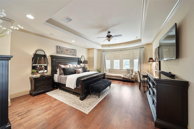 bedroom with a tray ceiling, visible vents, and wood finished floors