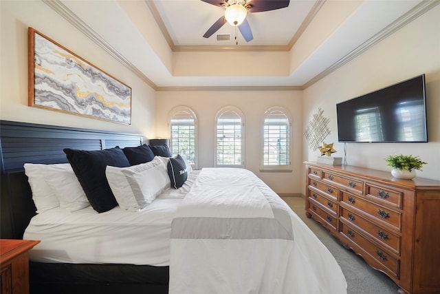 bedroom with carpet floors, visible vents, ornamental molding, and a tray ceiling