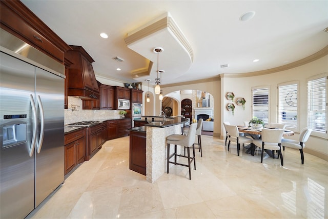 kitchen with tasteful backsplash, visible vents, decorative light fixtures, built in appliances, and crown molding