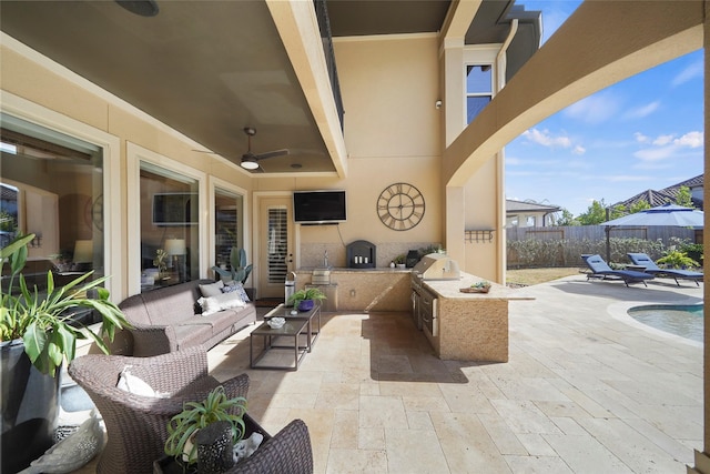 view of patio featuring a fenced backyard, an outdoor kitchen, a ceiling fan, and an outdoor living space