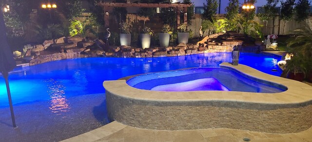 view of swimming pool with a pool with connected hot tub and fence