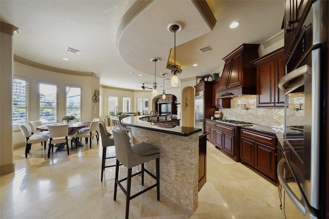 kitchen with arched walkways, pendant lighting, visible vents, and dark stone countertops