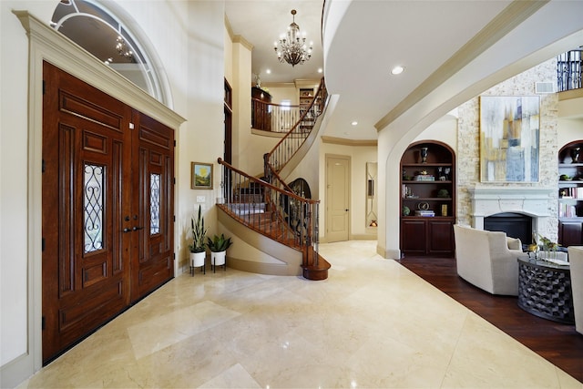 entryway featuring baseboards, stairway, crown molding, a fireplace, and a chandelier