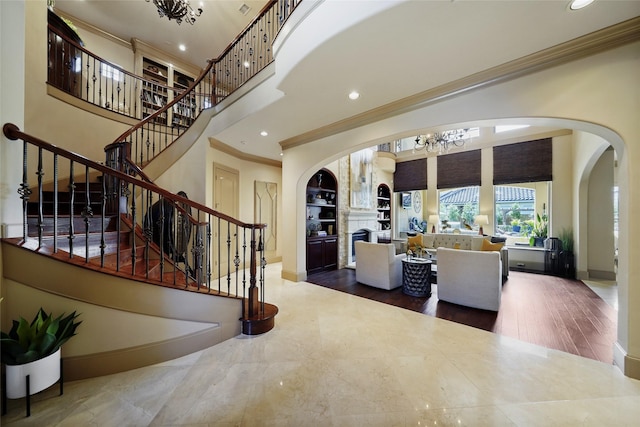 entrance foyer with a towering ceiling, baseboards, arched walkways, and ornamental molding